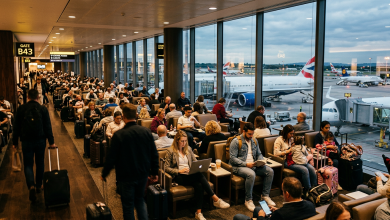 Passengers seated and walking in busy airport terminal at gate B43 with planes outside